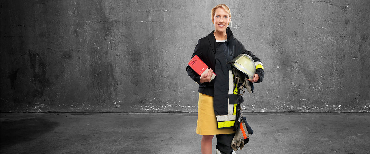 Fotomontage eine Frau: Halb Juristin in schwarzem Blazer und gelbem Kleid, halb Feuerwehrfrau in Uniform. Sie hält ein rotes Buch mit Gesetzestexten in der Hand.