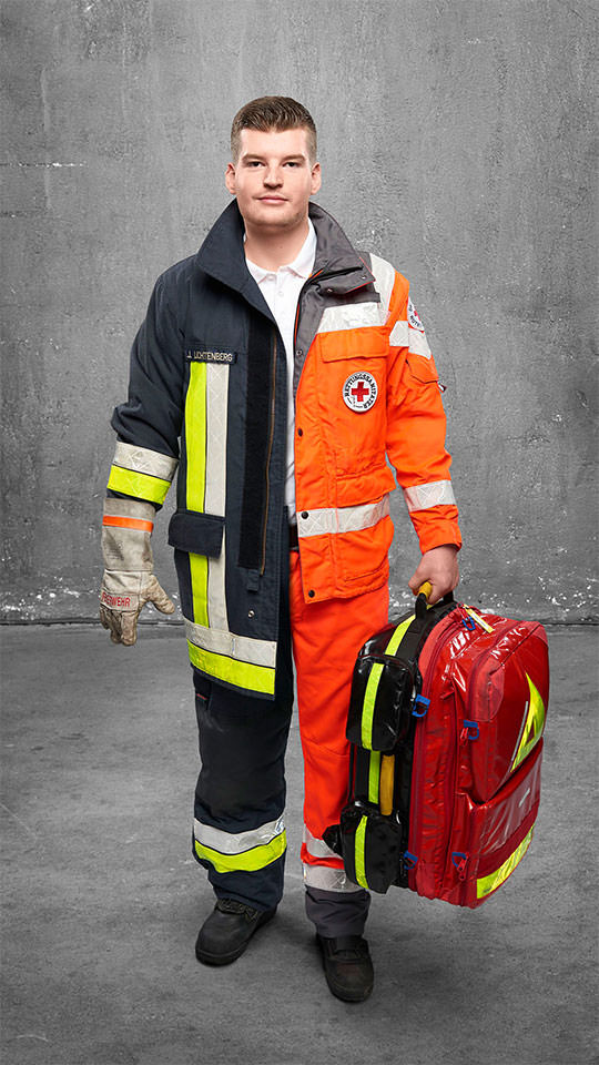 Fotomontage eines Mannes: Halb Rettungsassistent in Arbeitskleidung, halb Feuerwehrmann in Uniform. Er trägt einen Rettungsrucksack.
